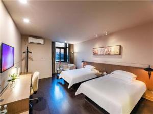 a room with two beds and a desk and a room with at JinJiang InnSelect Suzhou Shengze Shunhuxilu Hotel in Suzhou
