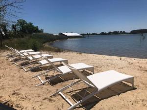 a row of lounge chairs on a beach next to the water at The Quarters at Pier450 in Ridge