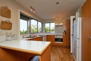 a kitchen with wooden cabinets and a white refrigerator at The Lookout, Spacious, Stunning Views - KK12632 in Kaikoura