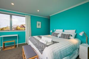 a blue bedroom with a large bed and a window at The Lookout in Kaikoura