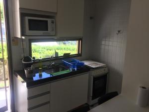 una cocina con fregadero y microondas en Flat Monte Castelo - Gravatá, en Bezerros