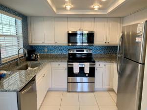 a kitchen with white cabinets and a stainless steel refrigerator at Island House Beach Resort 36 in Point O'Rocks