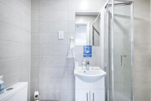 a white bathroom with a sink and a shower at Securematics Superior Studio Apartments in London