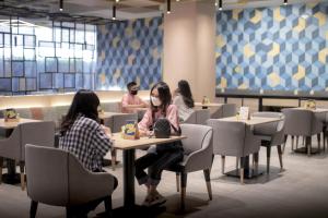 فندق يللو باسكال باندونغ في باندونغ: أناس يجلسون على الطاولات في مطعم يرتدون أقنعة