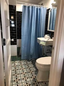 a bathroom with a toilet and a blue shower curtain at The Quarters at Pier450 in Lexington Park