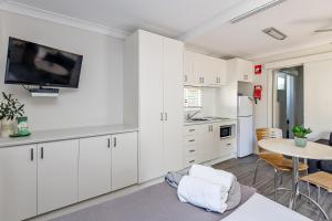cocina con armarios blancos y mesa con TV en Holiday Haven Burrill Lake, en Burrill Lake