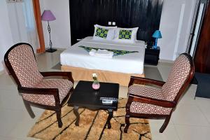a bedroom with a bed and two chairs and a table at Hotel BKBG in Lomé