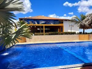 a villa with a swimming pool in front of a house at Recanto das Arvores in Barreirinhas