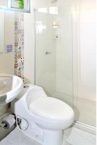 a white bathroom with a toilet and a sink at Hotel Las Margaritas Alojamientos in Barranquilla +33 photos