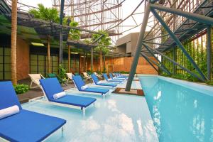 a swimming pool with blue chairs and blue umbrellas at Oasia Hotel Downtown, Singapore by Far East Hospitality in Singapore