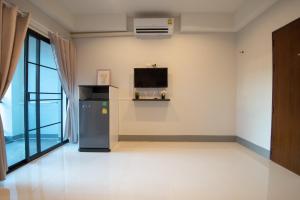 清莱J2 Residence Chiang Rai的一间设有冰箱和墙上电视的客房