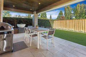 eine Terrasse mit einem Tisch, Stühlen und einem Grill in der Unterkunft Luxury Brand New Home in Shellharbour