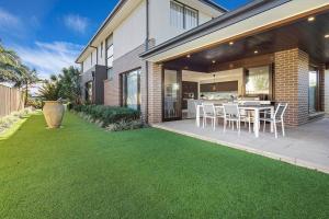 a patio with a table and chairs on a lawn at Luxury Brand New Home in Shellharbour