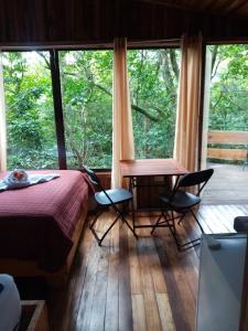 um quarto com uma cama e cadeiras e uma grande janela em The Green Tree Lodge em Monteverde