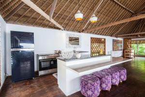 a kitchen with a counter and some purple stools at Villa GMB Beach house in Uluwatu