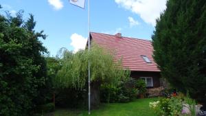 a red roofed house with a tree in the yard at Eule ost und west Ferienhaus im urigen Garten in Zingst
