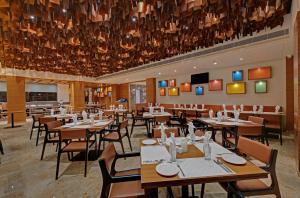 a restaurant with tables and chairs and a large chandelier at The Fern Royal Farm Resort, Anjar in Anjār