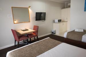 a hotel room with a bed, table and television at Admiralty Inn in Geelong