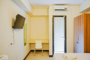 a room with a bed and a tv and a chair at Cozy Stay @ Studio 19 Avenue Apartment By Travelio in Porisgaga