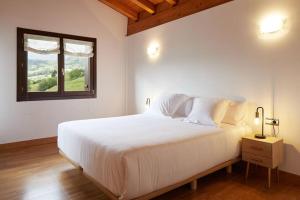 Schlafzimmer mit einem großen weißen Bett und einem Fenster in der Unterkunft Casa rural a 10 minutos de San Sebastian in Asteasu