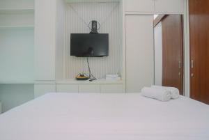ein weißes Schlafzimmer mit einem Bett und einem Fernseher in der Unterkunft New Furnished Studio Grand Kamala Lagoon Apartment By Travelio in Pekayon Satu + 8 Fotos