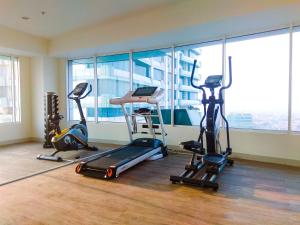 einen Fitnessraum mit Laufbändern und Trainingsgeräten vor einem Fenster in der Unterkunft New Furnished Studio Grand Kamala Lagoon Apartment By Travelio in Pekayon Satu