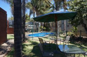 a table with an umbrella next to a pool at Mid City Plantation Motel in Mildura