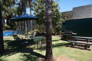 a table and chairs with an umbrella and a grill at Mid City Plantation Motel in Mildura