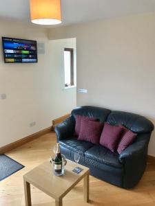 a living room with a black leather couch and a table at Oak Trees Corner stylish , relaxing , getaway in Wicklow