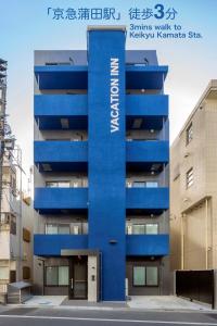 東京的住宿－VACATION INN KAMATA I，蓝色的建筑,旁边标有标志