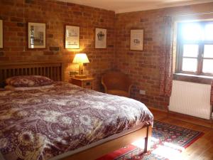a bedroom with a bed and a brick wall at The Motor House in Ledbury