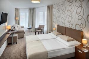 una camera con un grande letto e un soggiorno di Hotel Atlas a Benešov