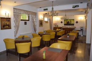 a restaurant with wooden tables and yellow chairs at Hotel Michelangelo in Bucharest