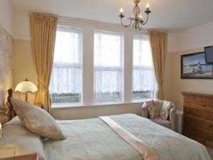 1 dormitorio con 1 cama y 2 ventanas en Amberlea Guest House, en Swanage