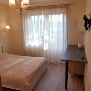 a bedroom with a bed and a table and a window at Apartamentai Vanagupės rajone in Palanga