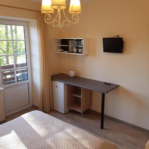 a room with a desk with a microwave and a window at Apartamentai Vanagupės rajone in Palanga