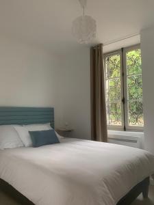 ein Schlafzimmer mit einem großen weißen Bett und einem Fenster in der Unterkunft Appartement Scandinave dans domaine historique d'exception in Vernaison
