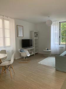 a living room with a tv and a table and chairs at Appartement Scandinave dans domaine historique d'exception in Vernaison