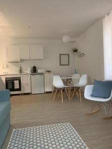 eine Küche mit weißen Schränken und weißen Stühlen in einem Zimmer in der Unterkunft Appartement Scandinave dans domaine historique d'exception in Vernaison
