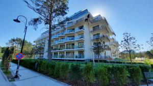 ein weißes Apartmenthaus mit einem Baum davor in der Unterkunft ApartPark Apartament Albus in Świnoujście