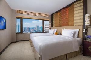 two beds in a hotel room with a view at The Garden Hotel Guangzhou in Guangzhou