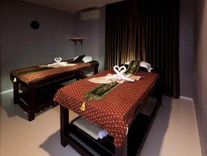 two twin beds in a room with a table at B Hotel in Khon Kaen