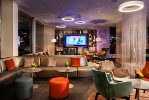 a lobby with a couch and chairs and a tv at Sunday am Main Taunus Zentrum Frankfurt Sulzbach in Frankfurt