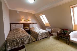 um quarto com 2 camas, uma cadeira e janelas em AllureInn Hotel and Spa em Chernivtsi