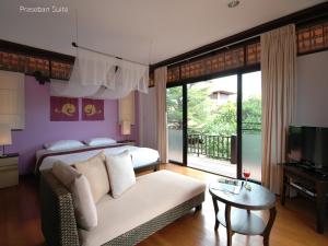 a bedroom with a bed and a couch and a television at Praseban Resort in Pran Buri