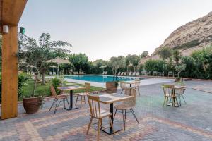a group of tables and chairs next to a pool at Matala Bay Hotel in Matala