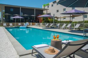 a swimming pool with lounge chairs and umbrellas at ibis Styles Pertuis Portes du Luberon in Pertuis +64 photos