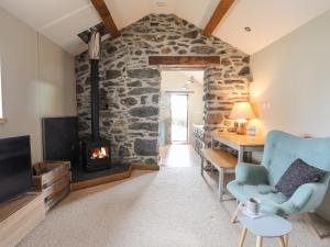 a living room with a fireplace and a stone wall at Ty Cerrig in Gaerwen