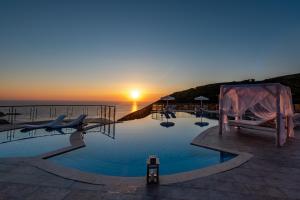a swimming pool with a sunset in the background at Petani Bay Hotel - Adults Only in Vóvikes