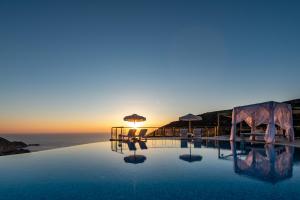 a pool with chairs and umbrellas and the ocean at Petani Bay Hotel - Adults Only in Vóvikes